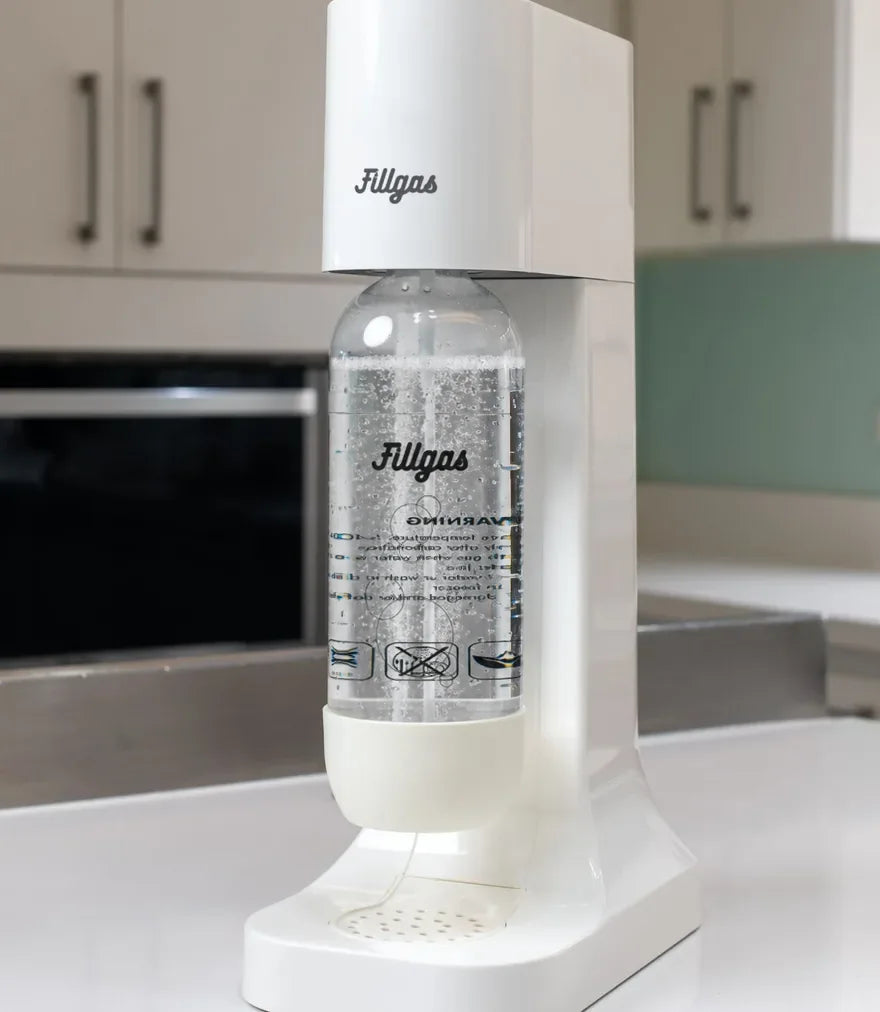 Máquina Fillgas branca na bancada da cozinha, com a garrafa cheia de água com gás